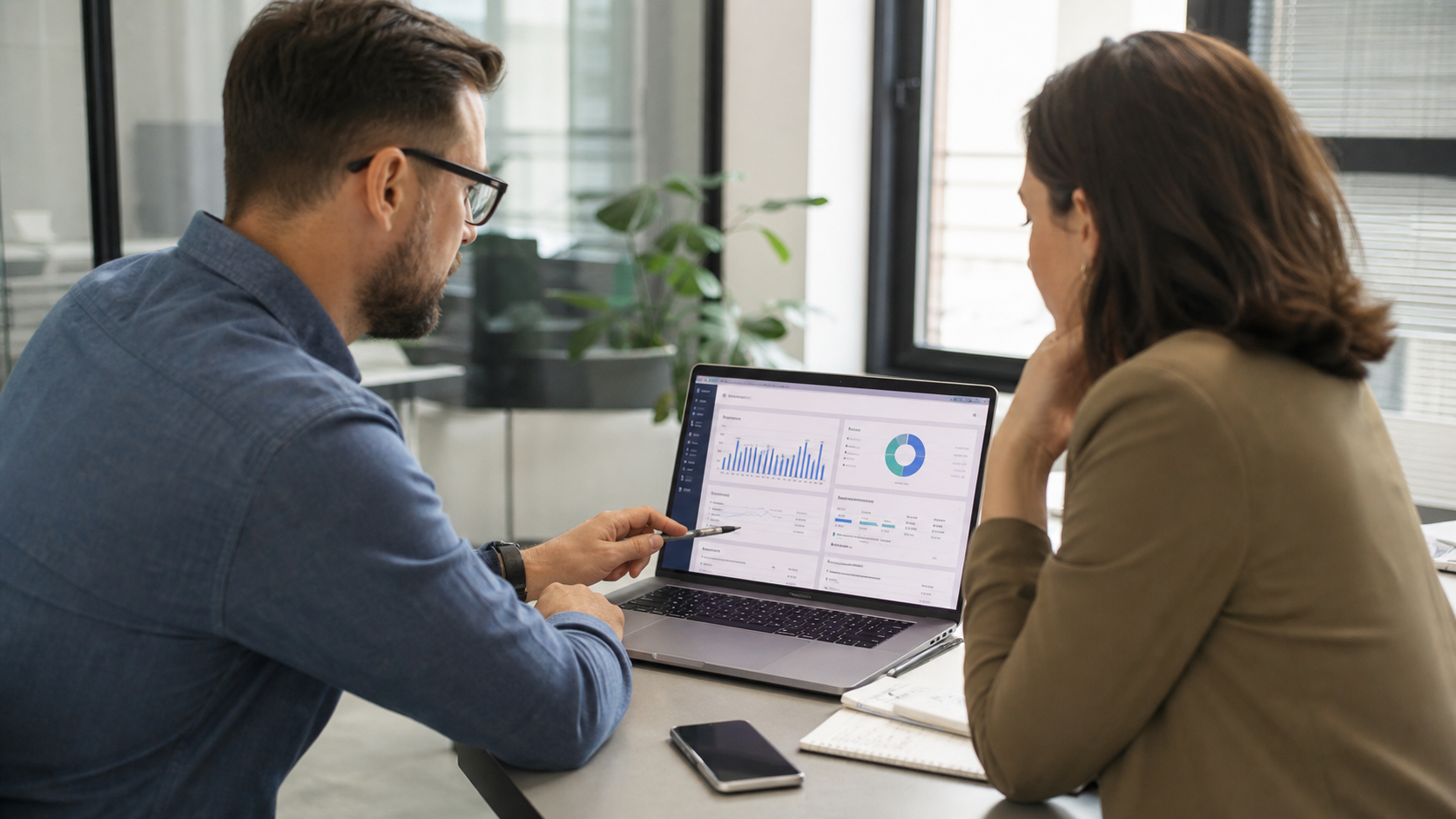 Manager de marketing și consultant analizând pe laptop rapoarte de call tracking și leaduri telefonice într-un birou luminos