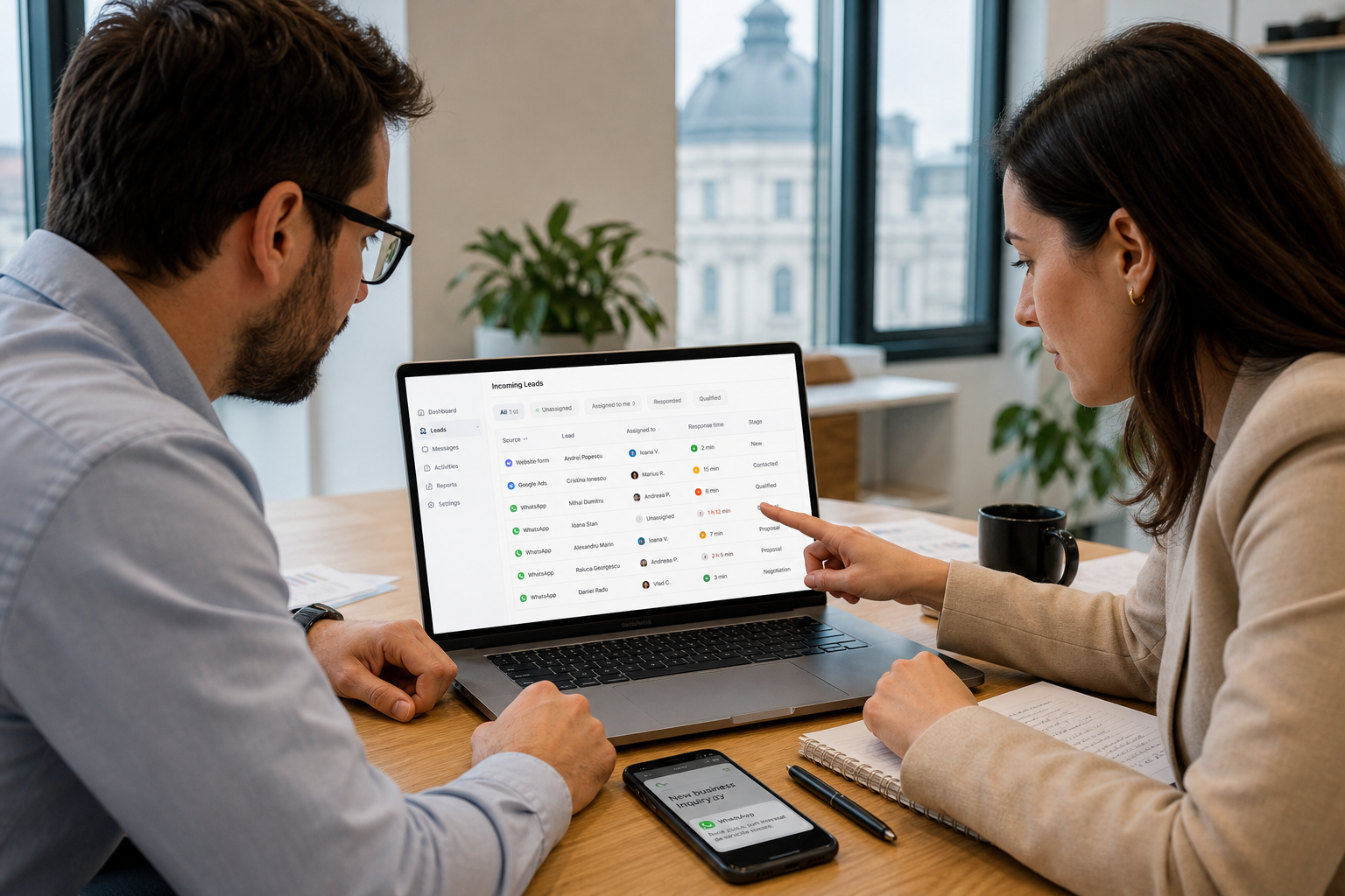 Manager de marketing și specialist de vânzări analizând pe laptop un dashboard cu leaduri venite din formulare, reclame și WhatsApp, într-un birou modern luminos